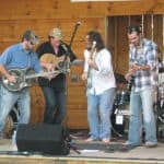 Band playing huddled together in the middle of the stage