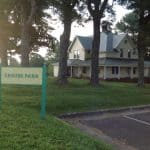 Crouse park sign with trees and house in the back