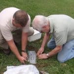 2 men setting stone into the ground